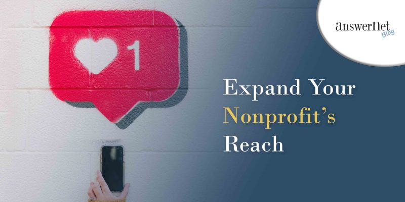 social media marketing - woman holding up phone against white cement wall with 1 heart notification